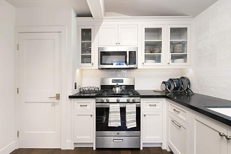 This modern, light-filled kitchen is designed for functionality and style. It features sleek stainless steel appliances  and a classic tile backsplash complete the clean, contemporary look.