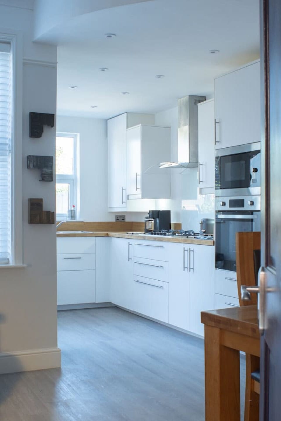 A well-equipped kitchen for preparing meals during your stay, showing white floor and wall units along two sides with natural light from the window.