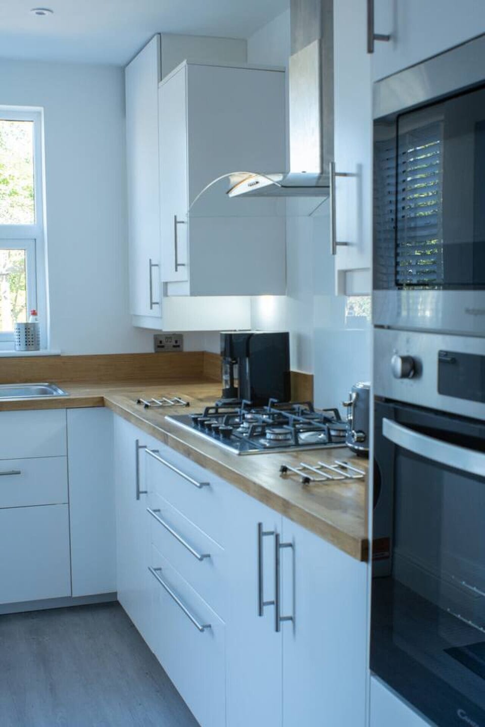 Kitchen worktop detail at counter level showing the gas hob controls, sink, and fitted white cabinets.