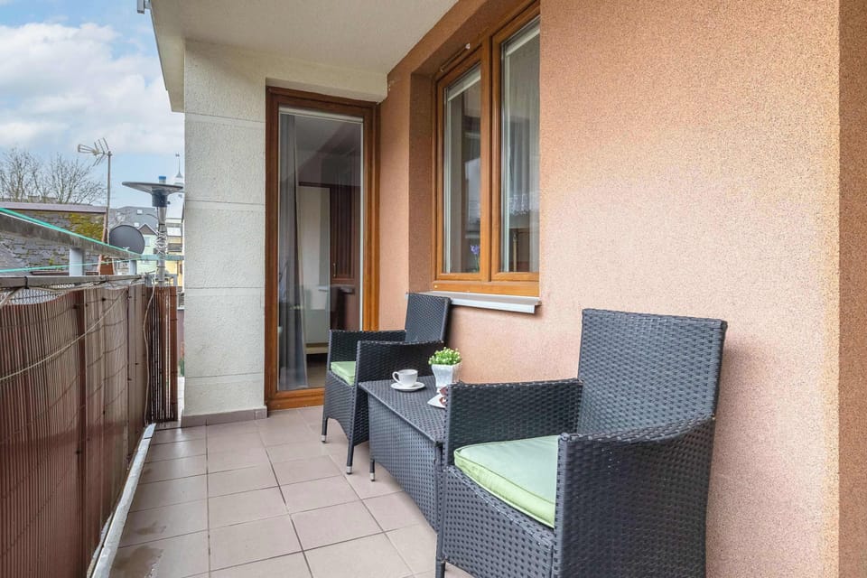 A private balcony is furnished with two comfortable rattan armchairs and a small table, offering a perfect spot for outdoor relaxation.