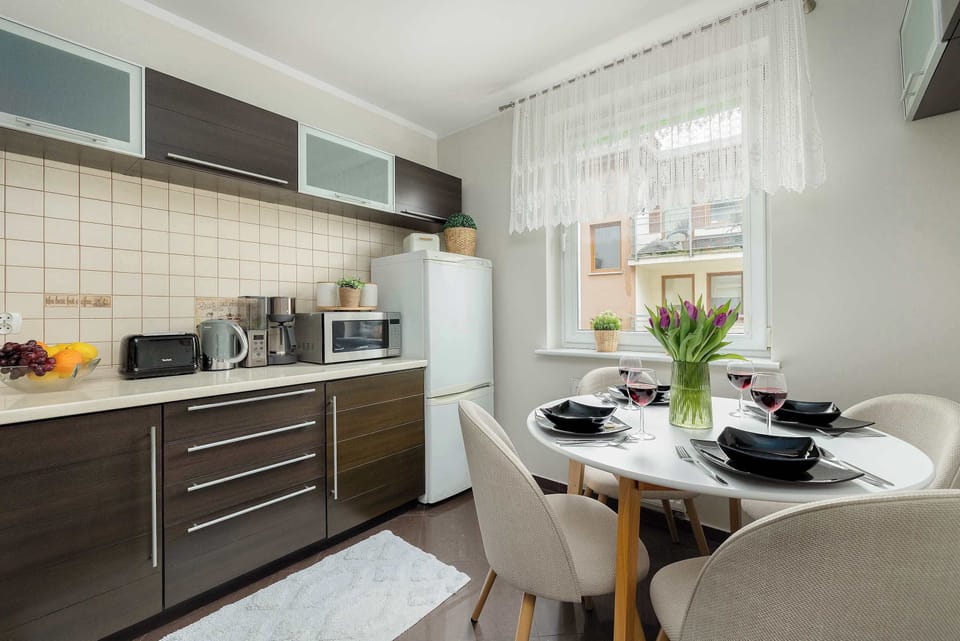 The kitchen's workspace is equipped with modern appliances, including a microwave and kettle, set against a backdrop of classic tiled splashbacks.