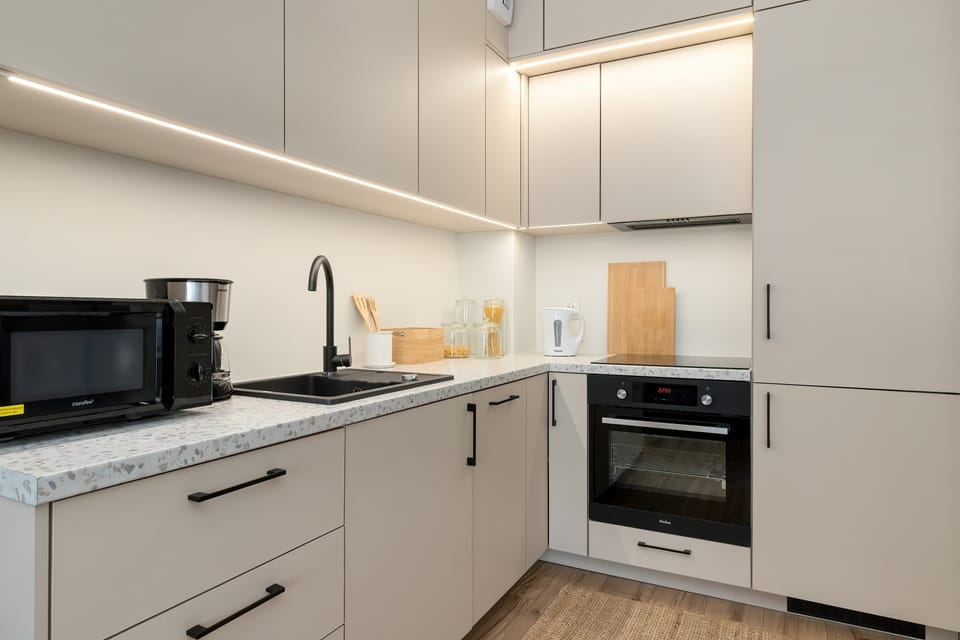 A close-up of the kitchen reveals high-quality appliances, including a built-in oven and a black microwave. Led strip lighting under the upper cabinets provides excellent illumination for meal preparation.