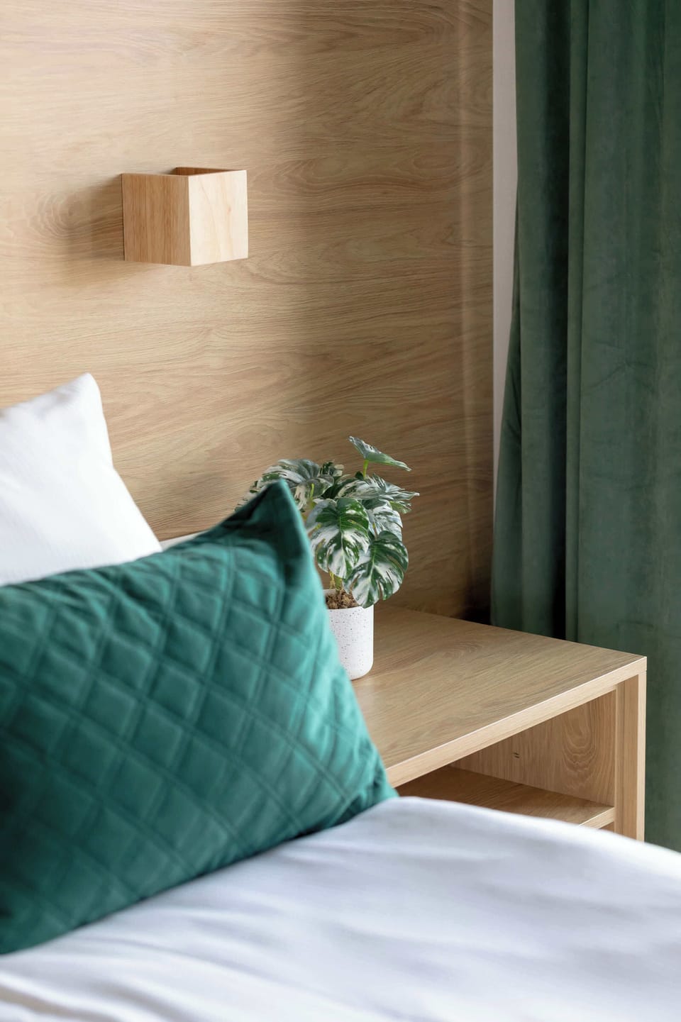 A close-up detail of pillows and bedding against a white wall. Textures and soft colors create a cozy impression.
