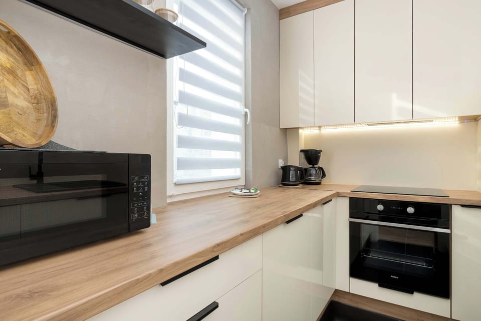 A closer look at the kitchen countertop with a built-in oven and stovetop. The wooden work surface and white cabinetry create a modern contrast. A window above the counter provides natural light.