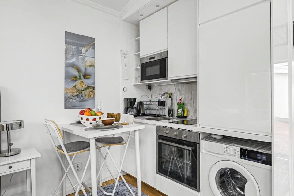 Compact kitchenette but functional kitchenette with oven, stovetop, fridge, microwave, coffee maker, and in-unit washer. Suitable for simple meals.
