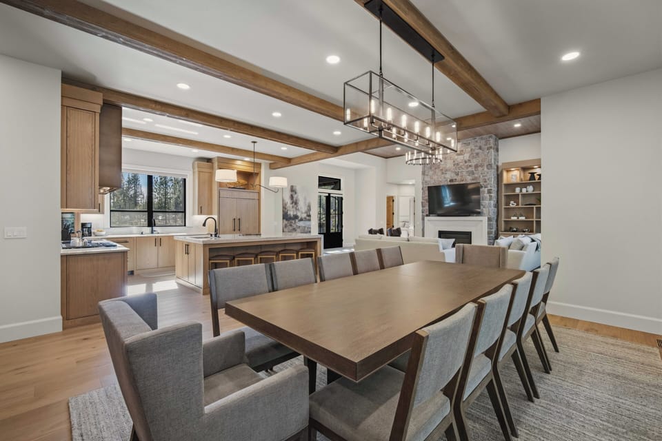Gather around this stunning dining table where memorable meals unfold beneath warm wooden beams and elegant lighting.