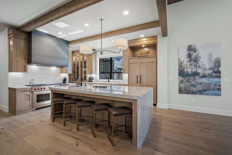 Gather around this stunning kitchen island where culinary adventures await, featuring marble countertops and rustic beams overhead.