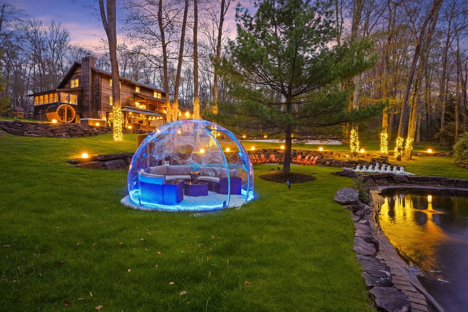 Illuminated igloo dome tent beside private pond in magical Pocono backyard setting
