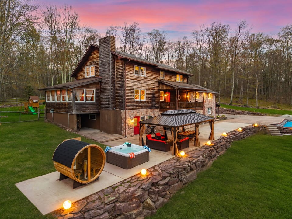 Exterior rear patio at dusk featuring barrel sauna and private hot tub