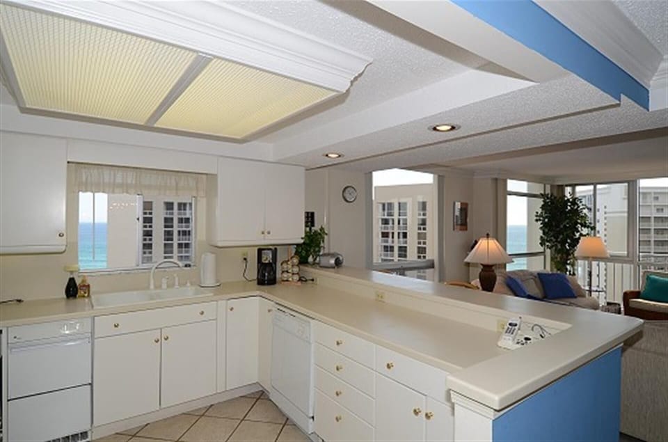 Your fully equipped kitchen awaits with pristine white cabinetry, spacious countertops, and stunning ocean views through charming glass-front cabinets.
