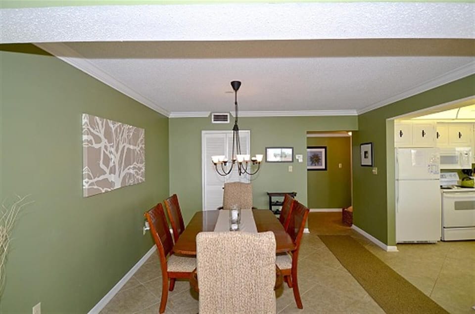 Gather around this stylish dining table where warm green walls and elegant chandelier lighting create the perfect atmosphere for your shared meals.