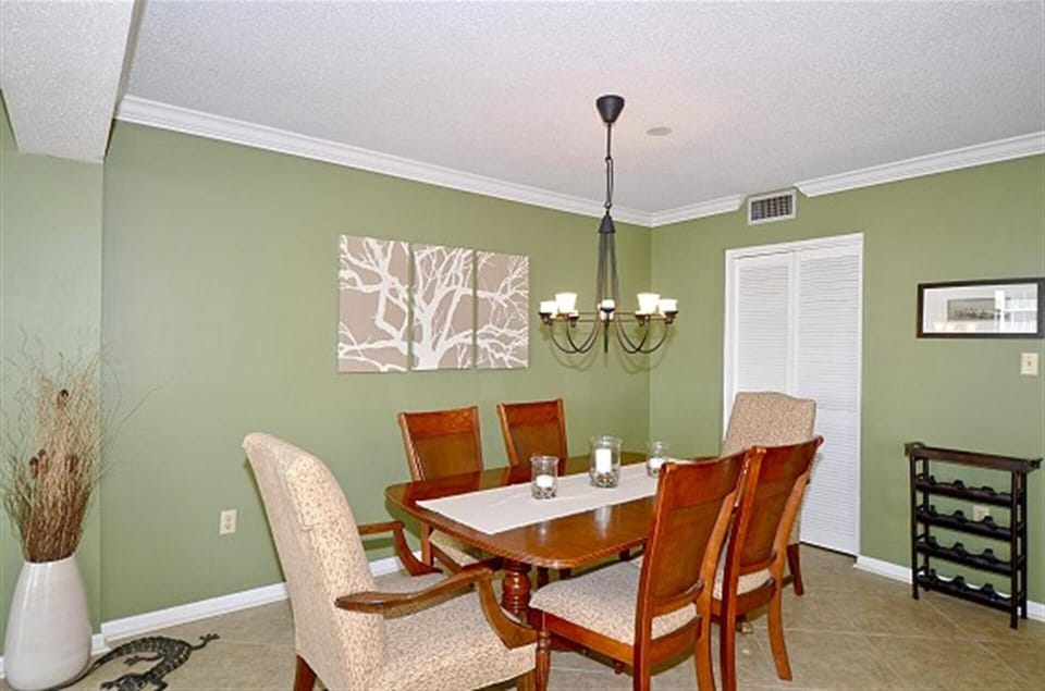 Gather around this elegant dining table where memorable meals await, surrounded by calming green walls and warm lighting.