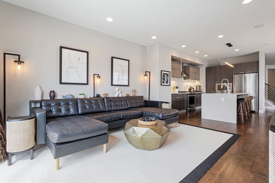 Settle into your sleek living space featuring a plush leather sectional, modern kitchen, and thoughtful design details that make every moment feel effortlessly comfortable.