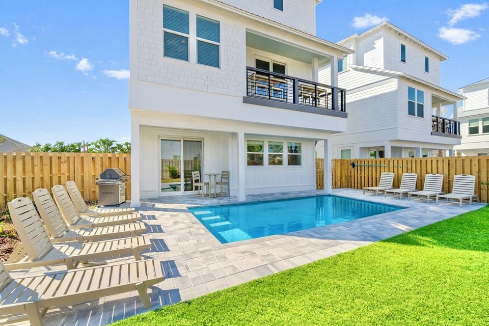 Oceans East—your perfect group getaway that SLEEPS 22! Just steps from the beach, this stunning retreat includes a FREE golf cart. Unwind in the backyard oasis with a HEATED pool, outdoor kitchen, and lounge seating.