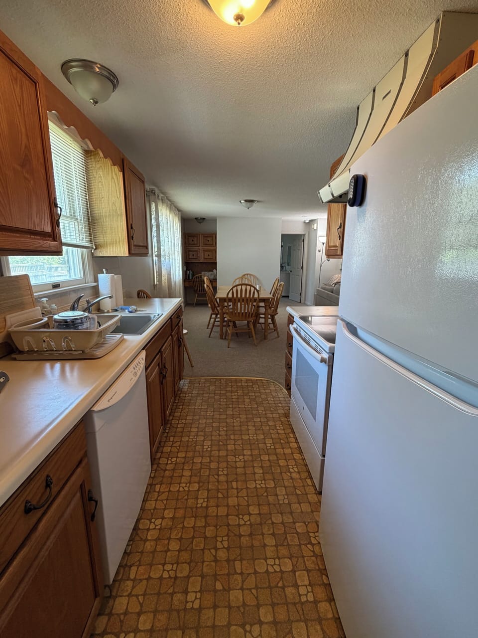 Galley kitchen with view of eating area and small desk.