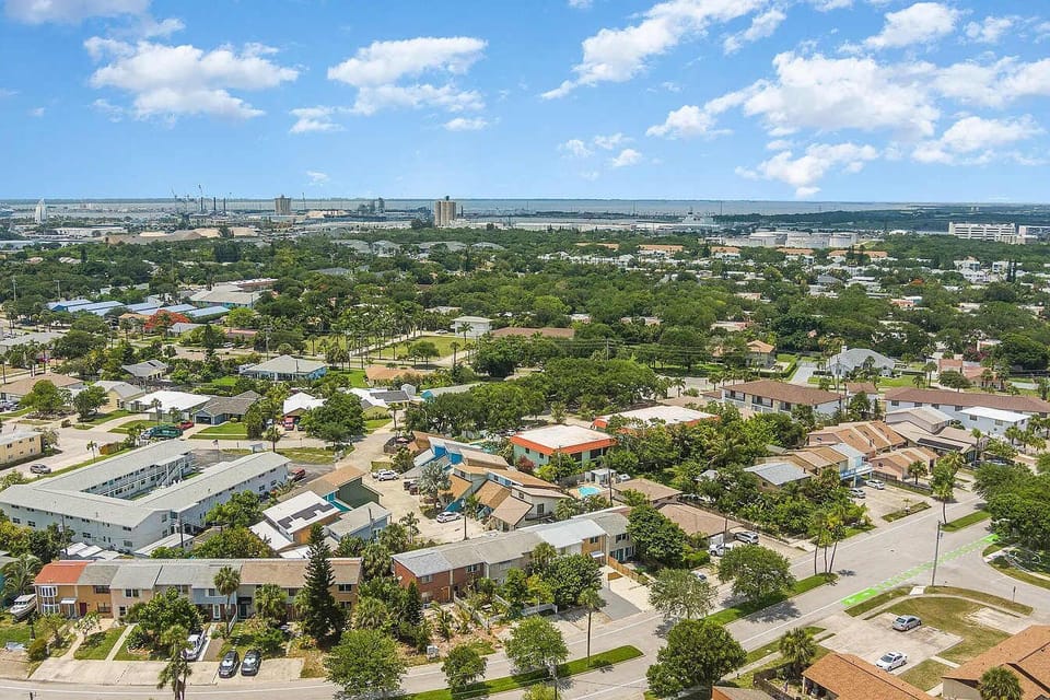 Aerial view of a residential neighborhood with lush greenery and clear skies.