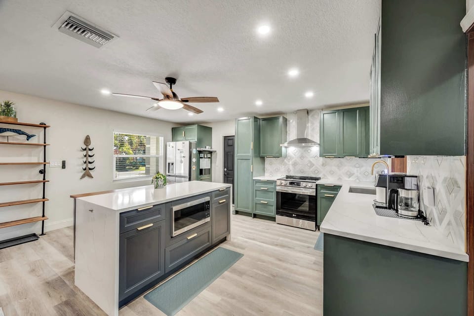 Modern kitchen with green cabinetry and a large island for cooking and gathering.