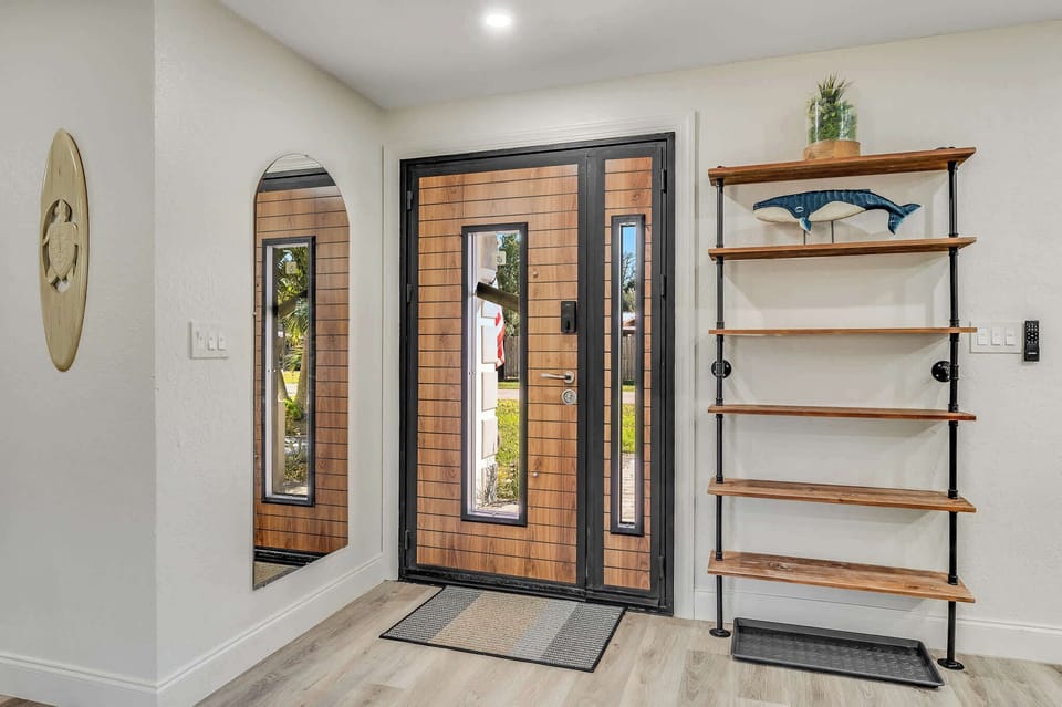Entryway featuring a modern wood and glass front door with a decorative shelving unit.