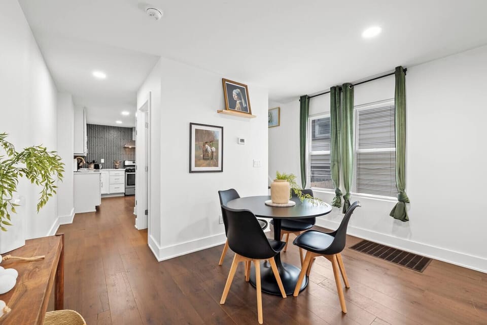 Stylish, open-concept living area featuring comfortable seating, modern decor, and a dedicated dining space for four. The bright room with dark wood floors is perfect for relaxing, connecting, and enjoying meals.