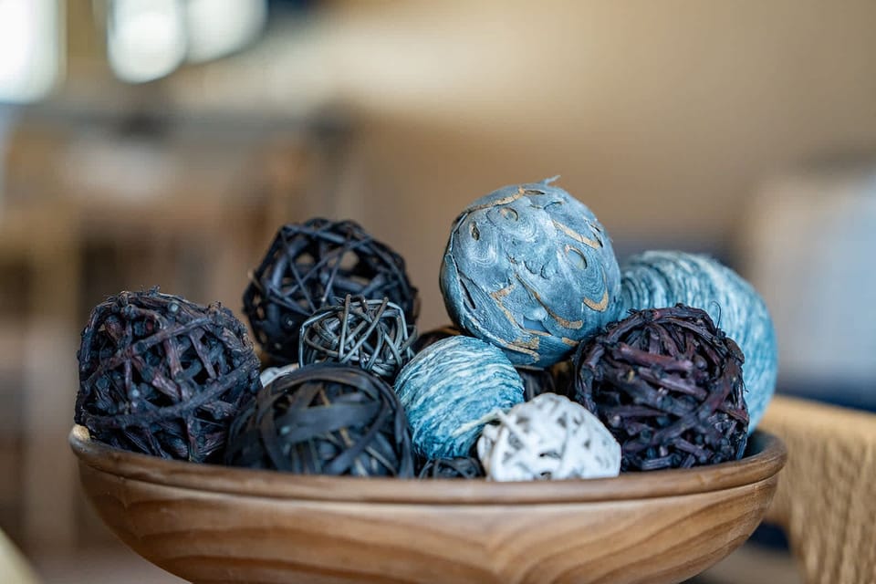 Decorative woven balls in a wooden bowl add a rustic touch to the living space.