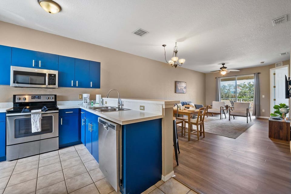 Open-concept kitchen and living area with blue cabinetry and natural light from the balcony.