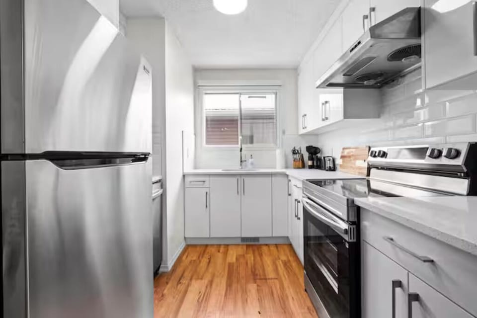 Modern, white kitchen with stainless steel appliances and ample counter space.