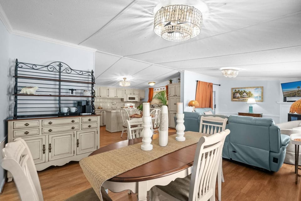 A cream buffet with dark wood shelves and coffee station stands against pale blue walls near the dining table.