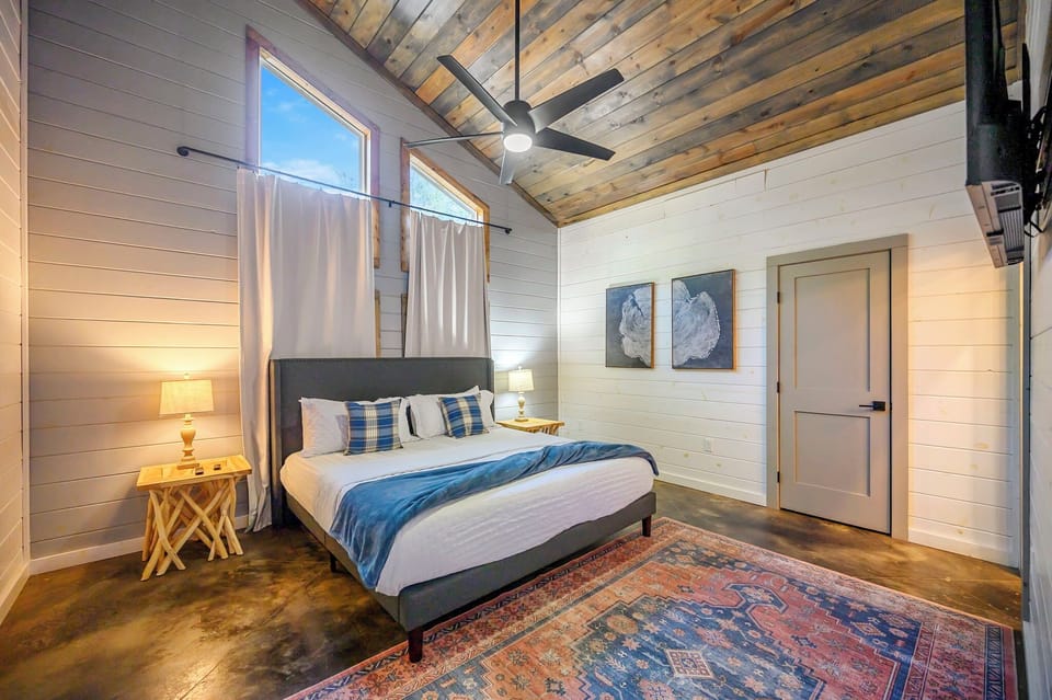 Serene king suite with vaulted wood ceiling, shiplap walls, and cozy modern style