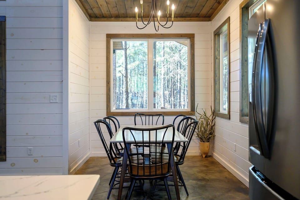 Bright dining nook with forest views, modern chandelier & cabin charm