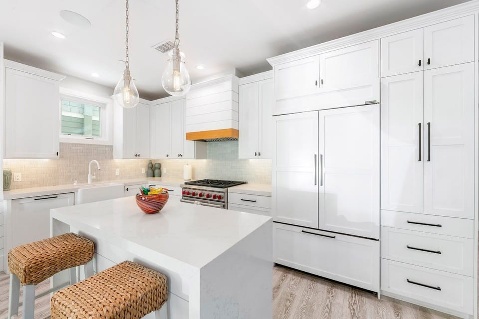 A focused view of the kitchen island and cabinetry, highlighting the clean design, waterfall countertops, and integrated appliances.