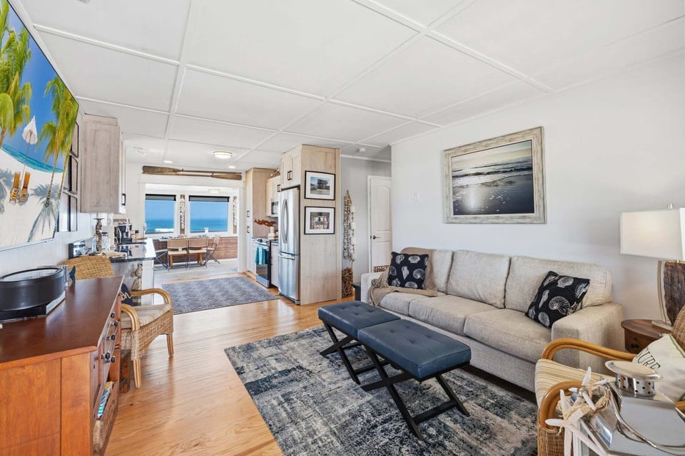 The bright and airy living room offers a comfortable gathering space where guests can relax together after a full day of beach adventures.