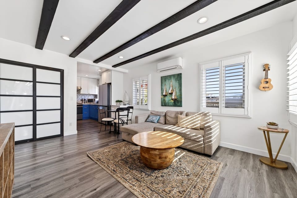 Relax in the open, sun-filled living area featuring comfortable seating and a Sony OLED TV with immersive sound bar—perfect for unwinding after a day at the beach.