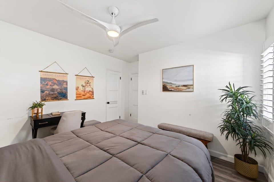 Enjoy a restful stay in a cozy bedroom featuring a plush queen bed, soft linens, and plantation shutters for a relaxing night's sleep.