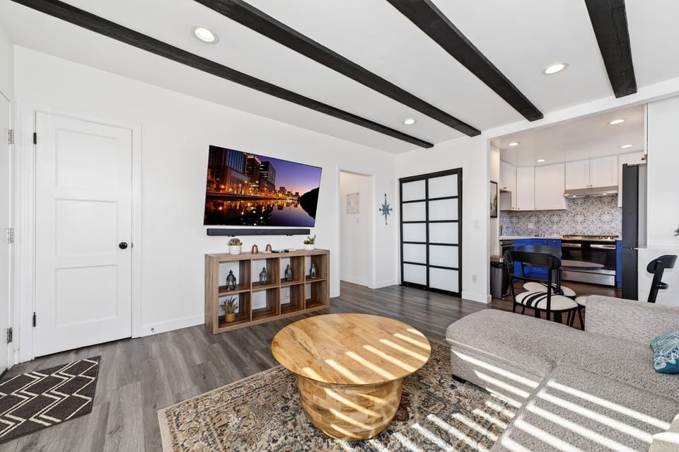 Relax in the open, sun-filled living area featuring comfortable seating and a Sony OLED TV with immersive sound bar—perfect for unwinding after a day at the beach.