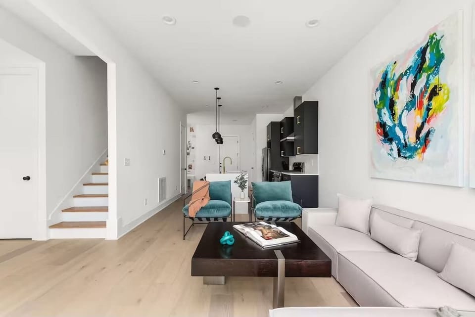 Bright and modern open concept living room with oversized windows, a comfortable sectional, bold artwork, and a Smart TV. (1st Floor)