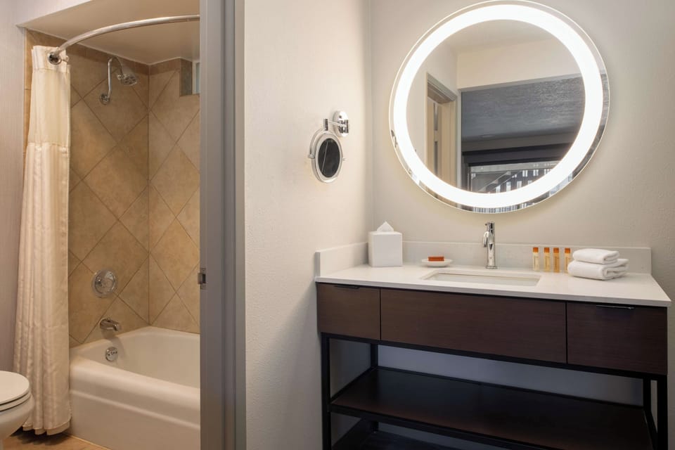 Refresh under a hot shower beside a glowing vanity mirror.