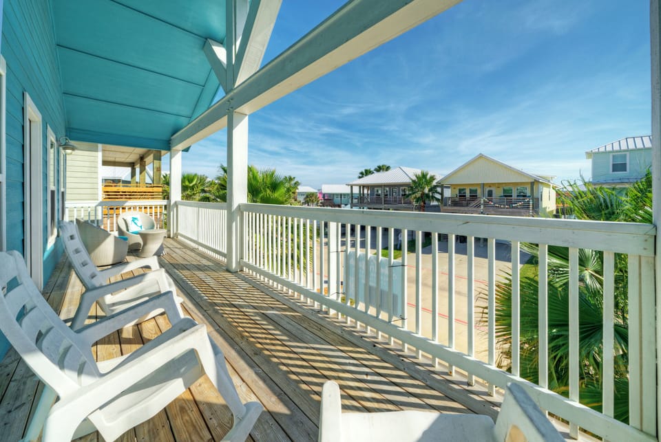 Sunny wraparound balcony with lounge seating and breezy neighborhood views.
