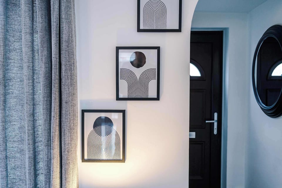 Thoughtfully styled wall with abstract art, soft curtains, and a modern mirror. A cozy, design-forward transition between rooms.