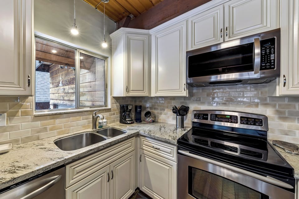 Your fully equipped kitchen features elegant granite counters, stainless appliances, and charming exposed beams overhead—perfect for preparing memorable meals.