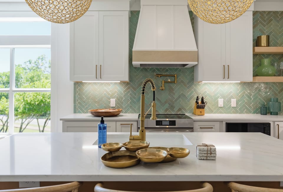 Gold fixtures and quartz counters give this kitchen a  luxurious coastal feel.