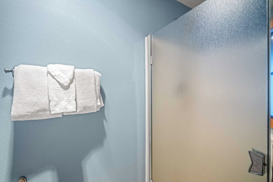 Fresh towels await your arrival in this clean, modern bathroom with soothing blue walls and thoughtful amenities.