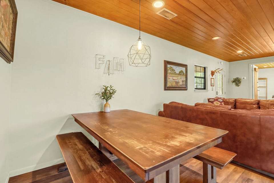 Your open dining space features a handsome wooden table with bench seating under warm wood-paneled ceilings and a geometric pendant light, perfect for memorable family meals.
