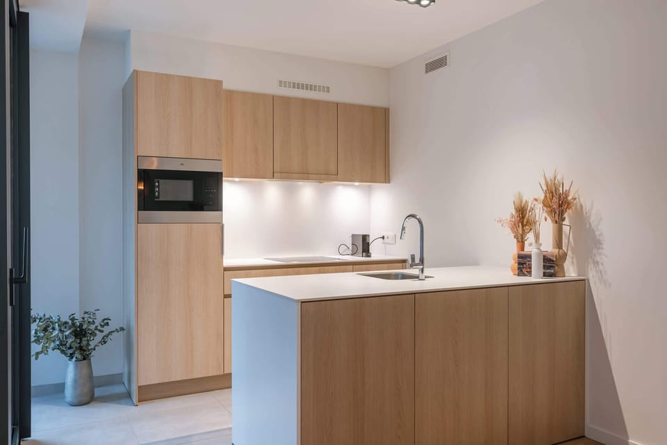 A warm, open-plan living space with a fully equipped kitchen and a dining table for four