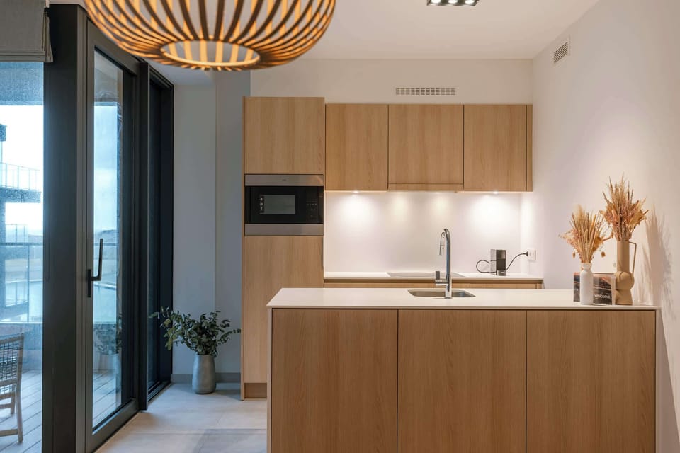 A warm, open-plan living space with a fully equipped kitchen and a dining table for four