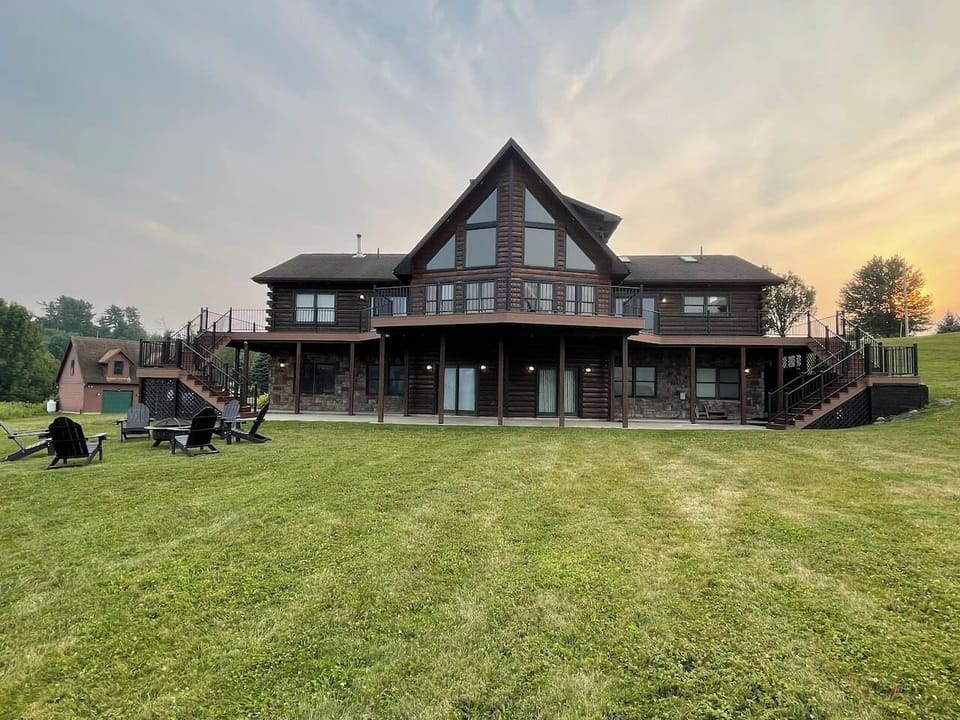 The backyard of this gorgeous log cabin is a dream in winter or summer with a full wraparound porch, fire pit, and double staircases. 