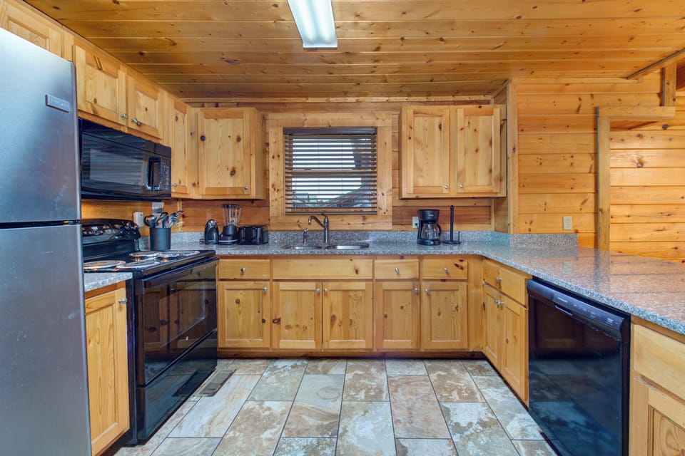 Your rustic mountain kitchen features warm wood cabinets, granite counters, and modern appliances for perfect cabin cooking.