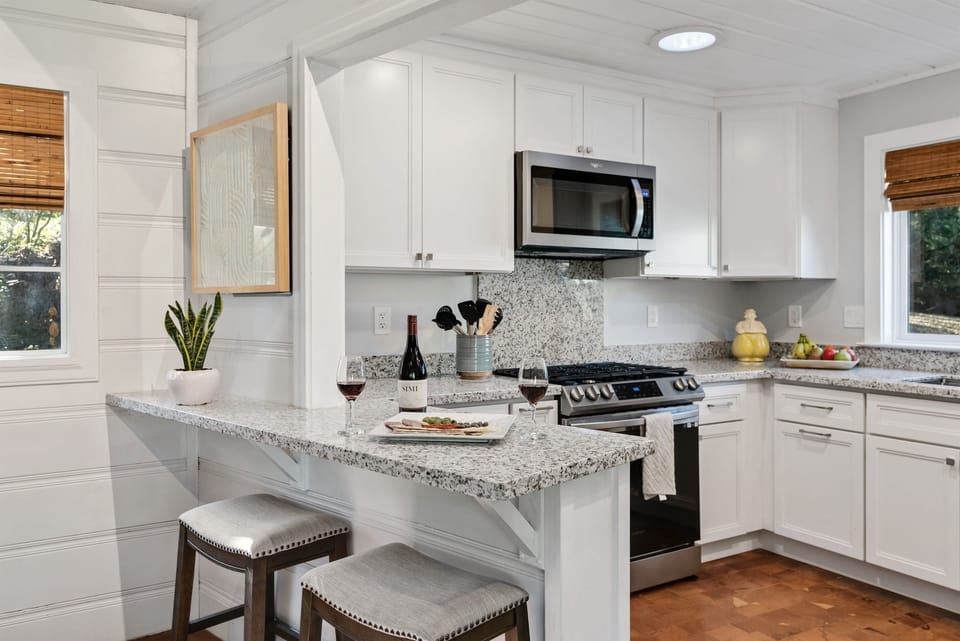 Bright chefs kitchen with granite countertops and stainless appliances.