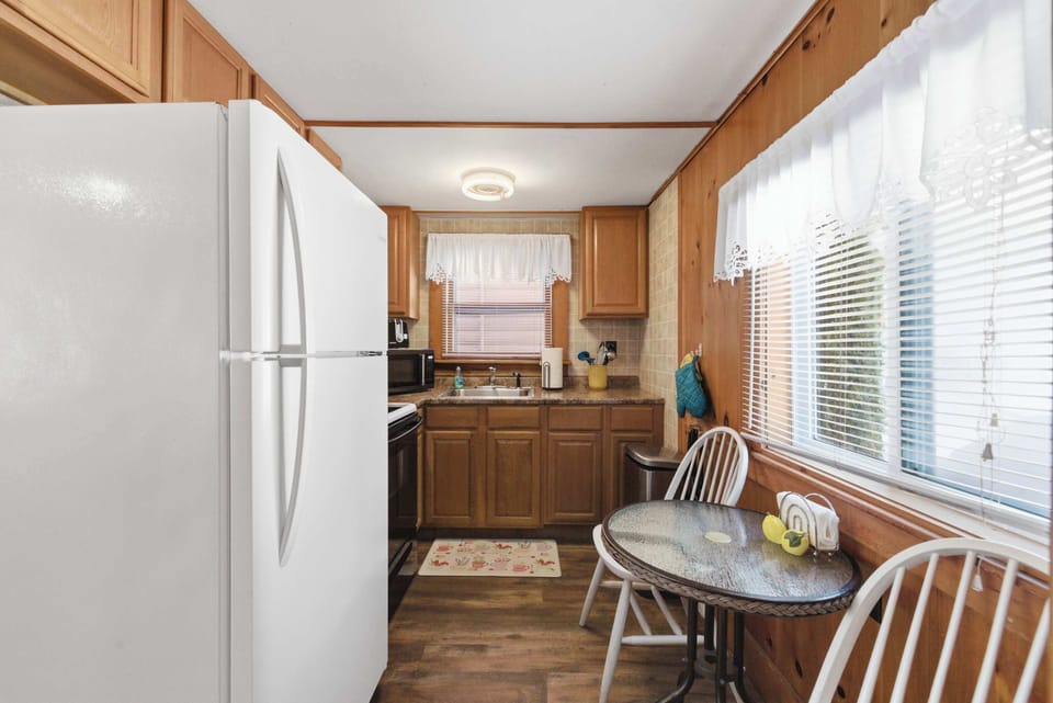 The kitchen runs along one wall with everything you need for real cooking, and a small table with chairs sits just around the corner near the window.