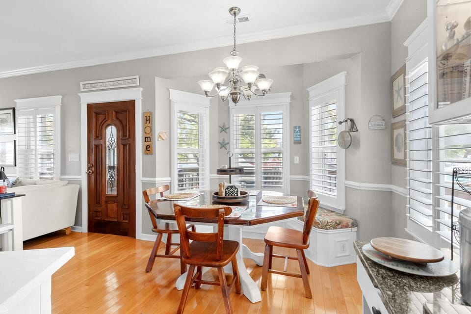 Sunlit dining area with elegant chandelier and hardwood floors