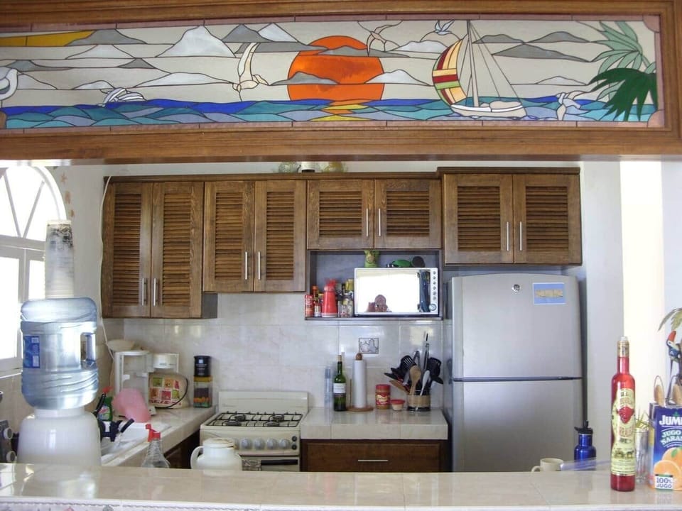 A fully stocked kitchen with a beautiful stained glass pictorial overhead. 